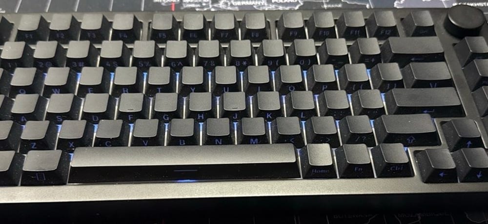 MonsGeek M1 V5 keyboard with blank black keycaps and a rotary knob, on a world-map desk mat